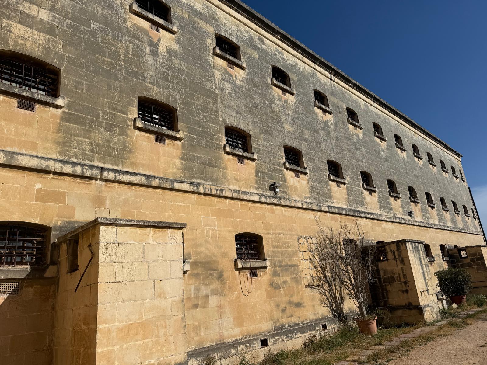 Kordin prison wall — barred windows, no modern road
